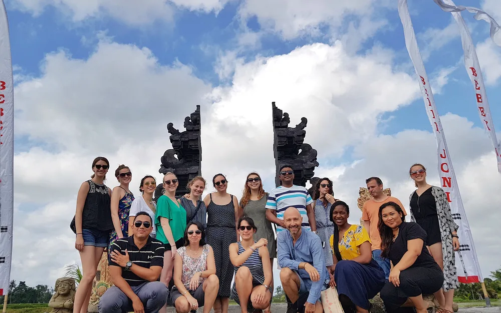 International students at a Balinese candi bentar split temple gate, exploring heritage and local wisdom in Indonesia