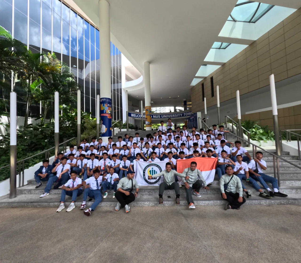 Large school group on an educational study visit with an institutional banner and Indonesian flag